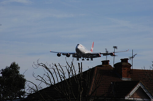 A plane flying close to houses.