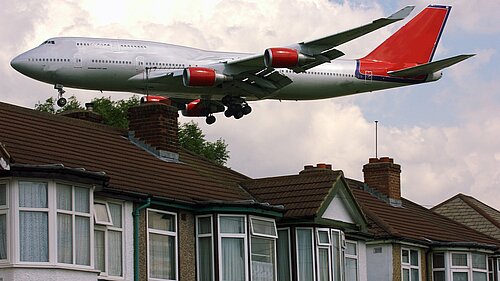 A plane flying close to houses.